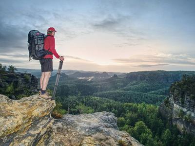 业余摄影师旅游摄影师与大相机日志和玄武岩三脚架手在山顶上的日落.